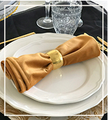 Elegant table setting with white plates, gold cutlery, and a wine glass.