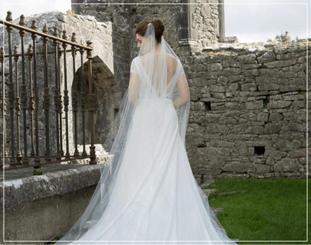 Bride standing beside castle ruins.