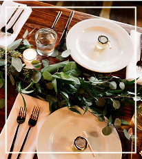Table settings with a leafy centerpiece running down the centre.
