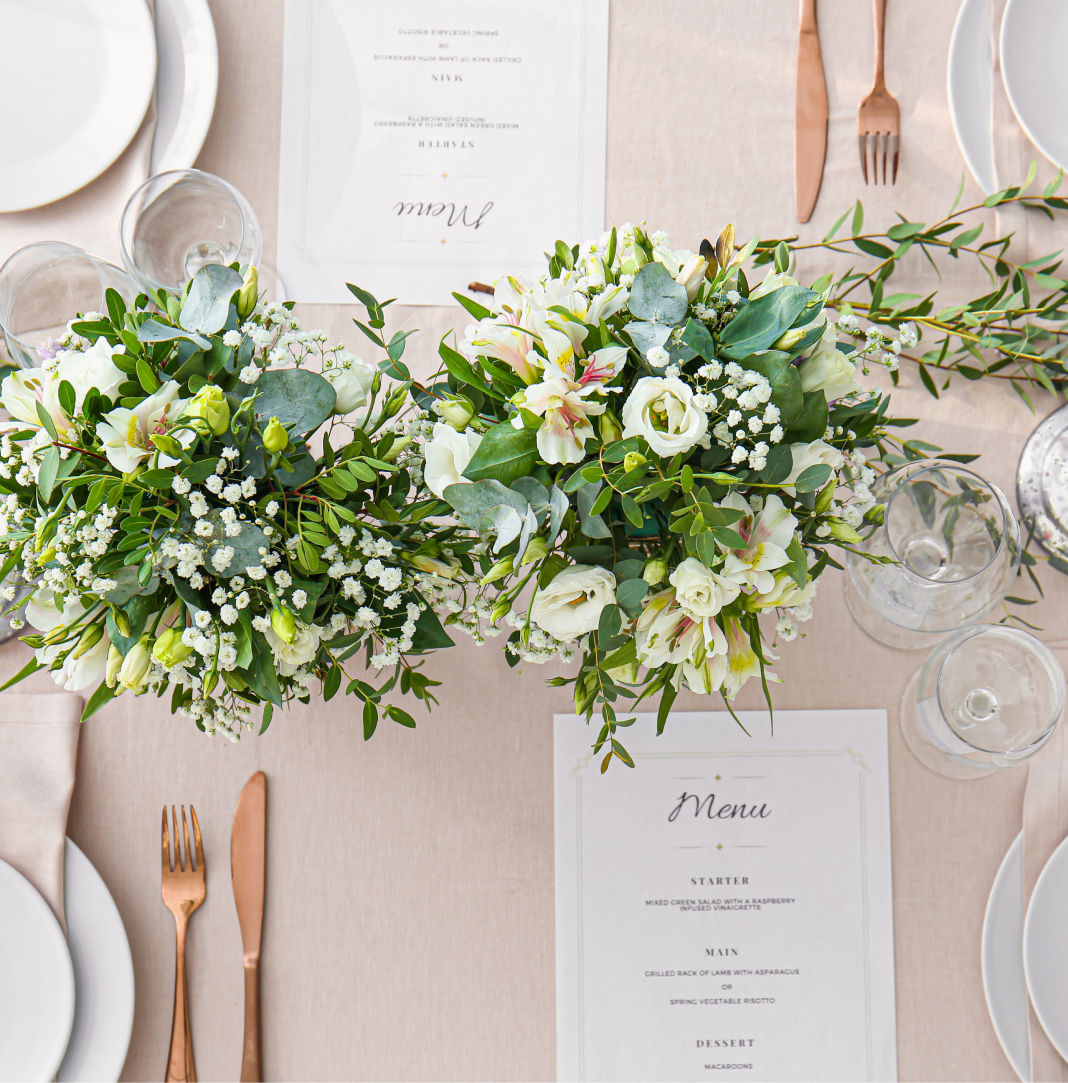 Table setting with floral centerpiece, gold cutlery, and menus.