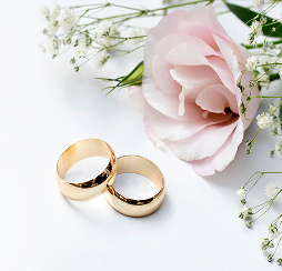 Two wedding rings placed on a table next to flowers