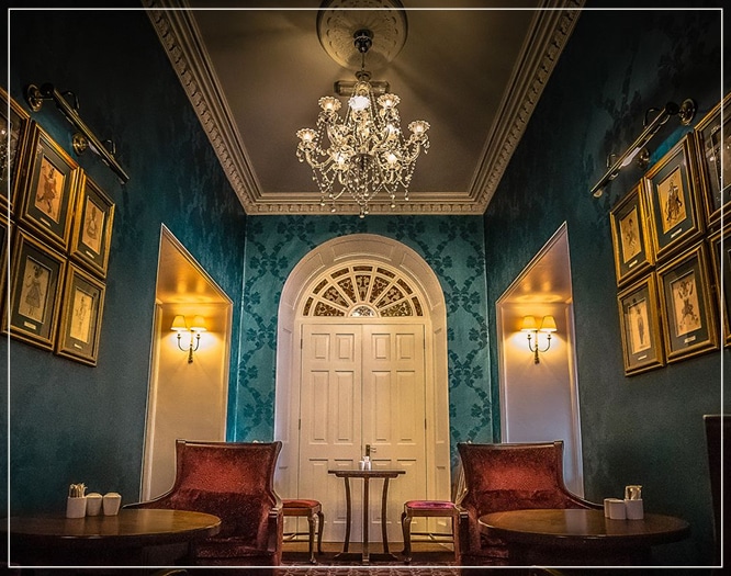 Luxurious hotel lounge with chandelier, velvet chairs, and ornate décor.