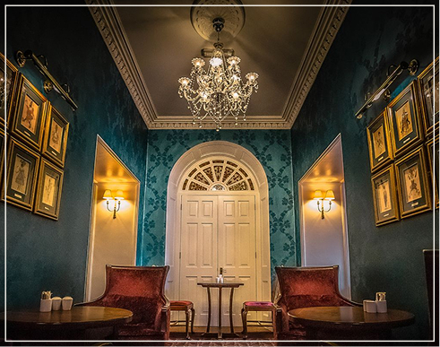Luxurious hotel lounge with chandelier, velvet chairs, and ornate décor.