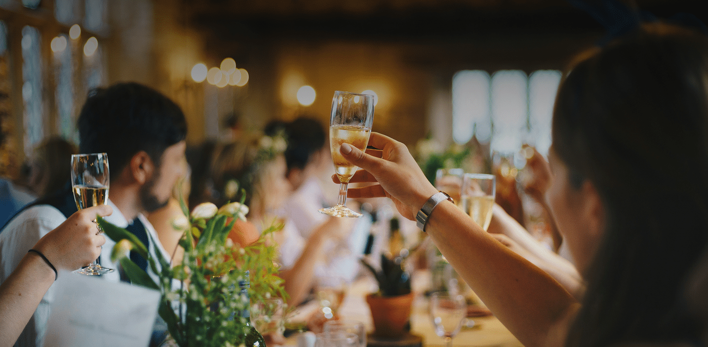 Wedding guests raising their glasses for a toast.