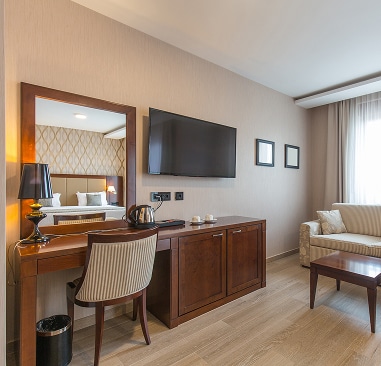 Hotel room with a dresser, TV, dressing table, and sofa