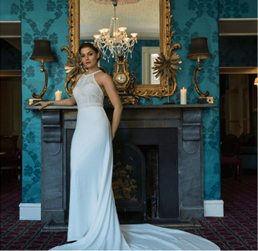A bride in a wedding dress posing near a cozy fireplace